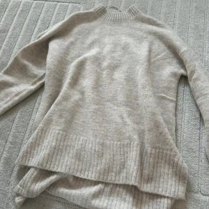 Stickad tröja! - Stickad tröja från ginatricot i en beige färg! Jätte bra skick! Bilderna är tagna i två olika ljus därav ser färgen lite olika ut men exakt samma tröja på båda bilderna! Tröjan är helt slutsåld! Kan gå ner i pris vid snabbt köp!