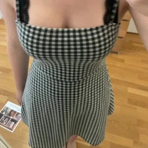 Svartvit rutig klänning från Divided - En svartvit rutig klänning från Divided. Klänningen har smala axelband och en åtsittande passform upptill med en något utsvängd kjol. Den är ärmlös och har en rakuringing. Den är i bra skick och inte använd många gånger.
