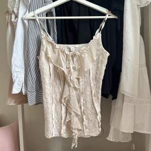 Spets/sidentopp - Topp med spets och sidendetaljer, färgen är cremevit men skiftar i lite rosa