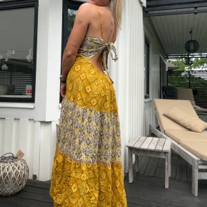 Gul sommar klänning - Använt ett fåtal gånger men inget tecken på slit överhuvudtaget!! Öppen rygg som man själv knyter hur löst, eller tajt man vill beroende på vilken look man är ute efter. Öppen detalj längst ner mellan de två färgerna (se bild) Så skön och flowig!! 