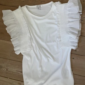 Söt vit tröja med volangärmar  - Söt vit, kroppsnära tröja med volangärmar. Storlek M men passar S. Knappt använd, säljs då den inte kommer till användning. 
