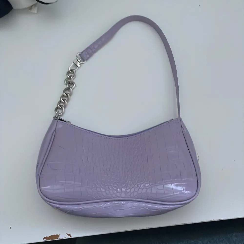 Säljer en lila handväska med kedja på halva handtaget🩷knappt använd men lite märken på som var innan jag köpte den.. Väskor.