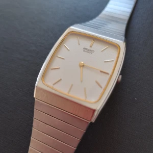 Seiko vintage armbandsur tank - Vintage Seiko armbandsur i tank-modell. Modellnumret är 8620-5150. Otroligt fin urtavla och sitter på orginalarmband (dock ej integrerat så det går att byta). Mycket bra skick för sin ålder. Bara ett nytt batteri som behövs. Mått 29x37mm.