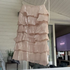 Skimrande volang klänning  - Säljer denna super fina klänning då den tyvärr är för kort för mig. Helt oanvänd bara testad. Helt slut på hemsidan. Är från Shein men bra kvalite ändå, dyrare variant då den är tillverkad tillsammans med Forever 21. Färgen är lite aprikos/ ljusrosa 