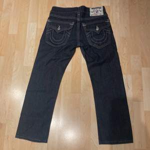 Ett par True Religion jeans med triple stitch i modellen ”Straight”. Storlekt W29 med midjemått 40 cm tvärsöver. Jeansen är nyskick, inga skador eller tecken på anvädning. Hör av er om ni har några funderingar! Billigare vid snabb affär! 