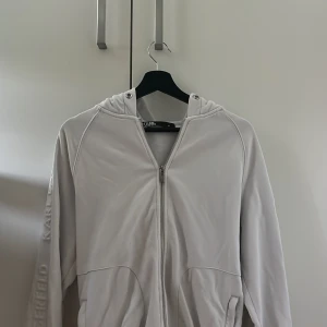 Karl Lagerfeld zip hoodie  - Vit Karl Lagerfeld zip hoodie i storlek M | Skick 9/10, använd ett par gånger men har inga defekter eller synliga fel. Nypris 2200kr, mitt pris 500kr, pris går att diskutera