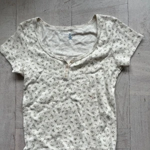 Tröja - Jättesöt coquette topp från brandy Melville med blommigt mönster, passar perfekt till sommaren. Tröjan är i onesize men skulle säga att den passar nån i storlek S/M