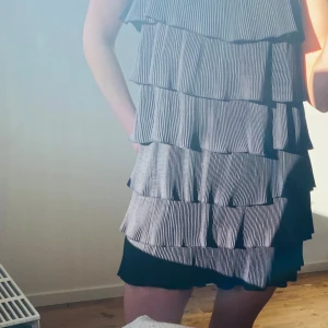 Klänning  - Svart klänning med volanger, smala band man knyter själv i ryggen. Använd fåtal gånger 