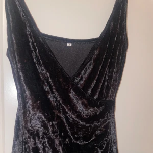 Svart sammet klänning med slits och korsning  - Svart sammet klänning. Okänt märke. Storlek S. Mycket skön och festlig. Har en ”slit” vid längst ned vid benet + korsning. 