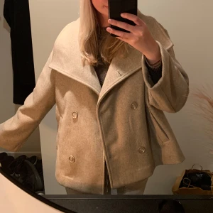 Kappa  - Superfin beige kappa till salu! Perfekt inför våren och varmare väder 🩷 Notera att den blivit något nopprig, och på ena ärmen finns ett hål, men där jag sytt fast en knapp som döljer hålet. 