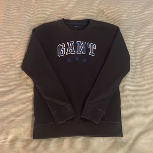 Gant sweatshirt - Marinblå Gant sweatshirt. Ser ut som svart på bilden men i verkligheten är den en jättefin marinblå färg, vilket man ser på andra bilden där jag lagt ett svart plagg brevid. Inga defekter förekommer. Storlek 146/152. Köpare står för frakt 