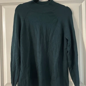 Långärmad grön tröja - En grön långärmad tröja med lite tyg upp vid nacken samt sitter åt vid slutet av armen. Använd fåtal gånger och säljer för att den är för liten.