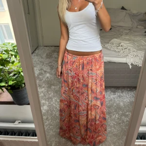 Mönstrad långkjol - Säljer denna rosa mönstrade långkjol. På bilden har jag vikt in ett resårband för att den ska passa mig i längden som är 162, går alltså att passa längre (skulle tippa upp till 175cm). Har du någon fråga är det bara att höra av dig🫶🏻