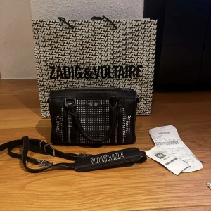 Zadig & Voltaire väska - säljer denna väska som är väldigt sällsynt. Modellen heter: XS SUNNY #2 GRAINED LEATHE. Skick: 8/10 inte använt så mycket men har en slitning på undersidan av väskan så den syns knappt som ni ser på bild 2. Nypris: 5000kr. Alla tillbehör ingår. 