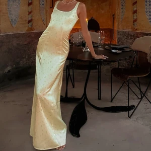 Ljusgul satinklänning med blommor NAKD - Säljer min magiska klänning endast använd under ett tillfälle. SLUTSÅLD!!! DIREKTPRIS 950 + frakt