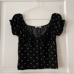 Prickig topp - Prickig topp från Stradivarius storlek M men mer som en S. Svart med vita prickar. Markerad vid bysten. Stretchigt material. Knäpps med knappar. Volang ärm. Använd men i fint skick. Bara att fråga om det är något du undrar! 