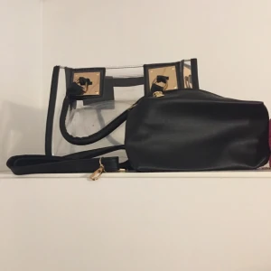 Väska - En fin genomskinlig väska passar regniga dagar med axelrem som går att ta bort och en svart lite nesesär . Jätte fin . 