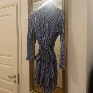 Knappt använd skjortklänningen i kornblå och vitt från POLO Ralph Lauren. Köpt i USA i april 2023 för 138 $, har kvittot kvar