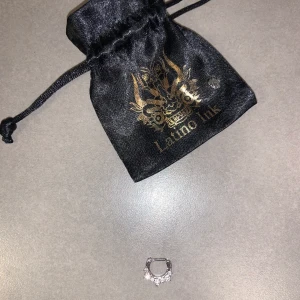 NY septum piercing från Latino Ink i Stockholm🤍 - Piercing med stenar från Latino Ink i Stockholm 🤍 Säljes pga fel storlek, oanvänd.   Clicker med gångjärn och 3 stora och 4 små Cubic zirconia-stenar. Material: Kirurgiskt stål Tjocklek: 1.6mm InnerDiameter: 8mm Köpt för: 199kr Säljes för 100kr