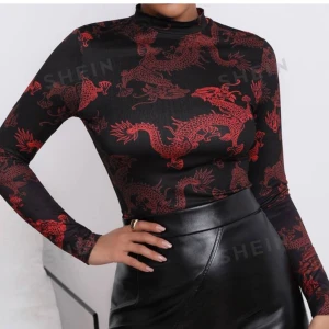 Fin topp med mönster - Fin tröja med drakmonster. Storleken är XL men det är lite tajtare passform än XL. Den är väldigt fin men jag rensar ut mina kläder och behöver plats i min garderob så säljer den nu så att någon annan kan få känna sig fin i tröjan. Skönt material 