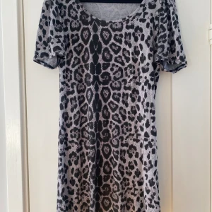 Svart och grå leopardmönstrad klänning i viskos från Ichi i strl L - Svart och grå leopardmönstrad klänning i viskos från Ichi i strl L.  Endast använd vid ett par tillfällen och är i väldigt fint begagnat skick.  Mått Över bröstet: ca 48 cm Längd från axeln och ner: ca 87 cm  95% viskos och 5% elastan  