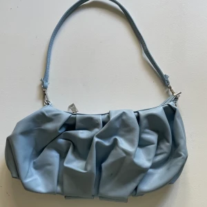 ASKUNGEN-BLÅ HANDVÄSKA - Gullig blå väska i läderimitation  Mått står under storlek  Pris kan diskuteras Mått: B= ca 30cm H= ca 14cm