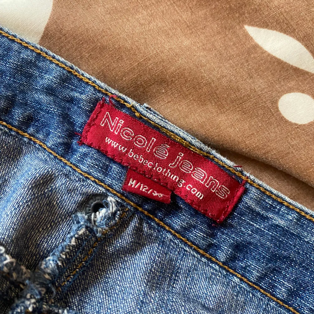 Supersnygga jeans med coola detaljer från tidigt 2000-tal  av märket Nicolé Jeans.  Midjemått rakt över: 39,5 cm Innerbenslängd: 84 cm Bredd längst ner: 25 cm. Jeans & Byxor.