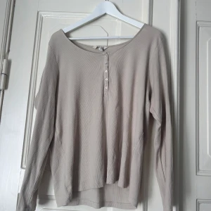 Långärmad tröja - Långärmad beige tröja med knappar upptill.