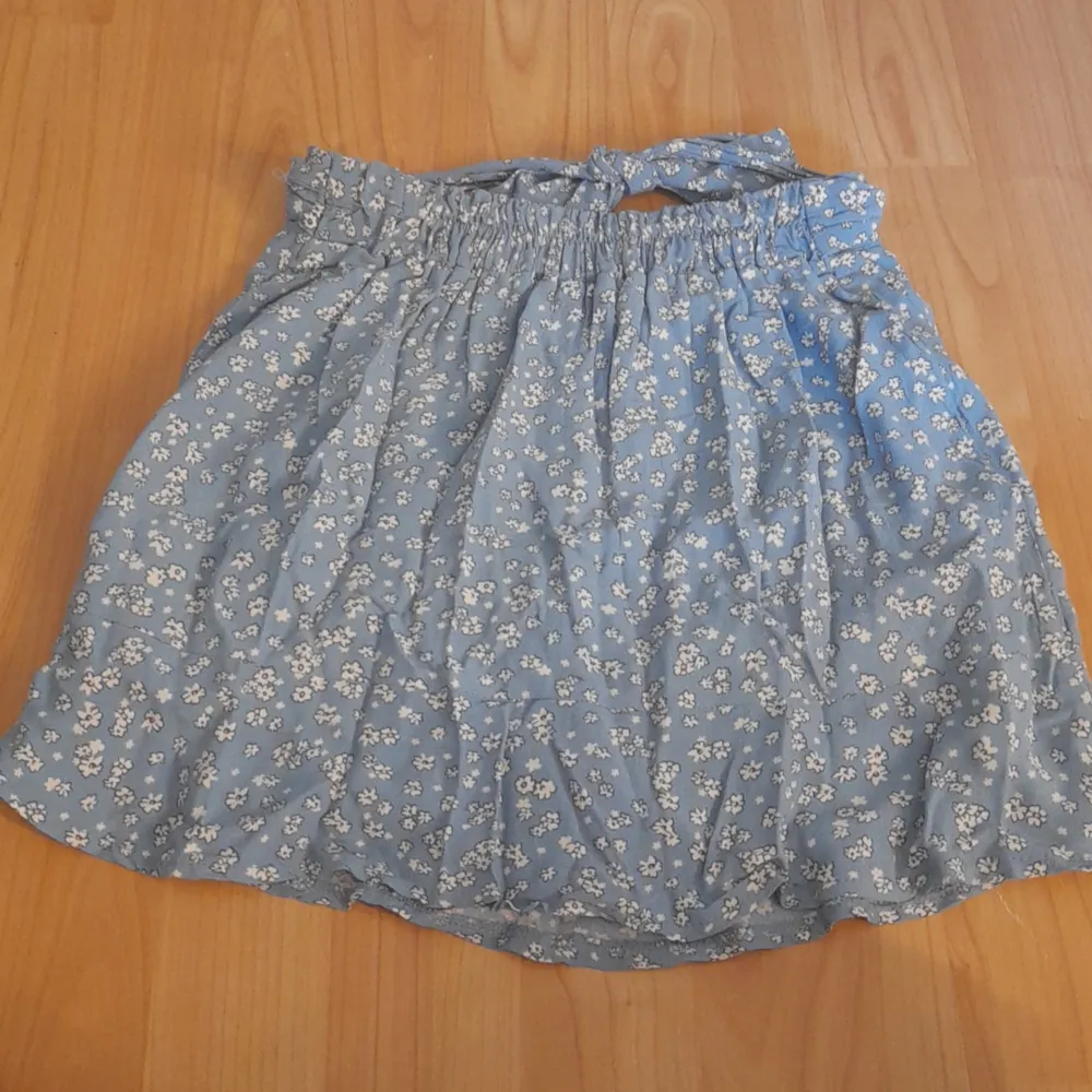 En kjol med shorts under. Kjolen är ljus blå med söta små vita blommor. Den har knyt funktion fram till och bak till så är den stretchig. Kjolar.