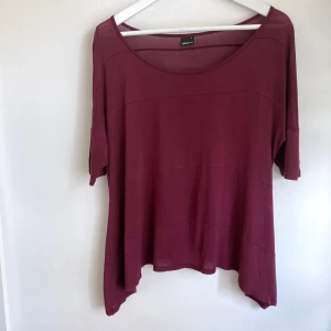 Burgundy draperad t-shirt, stl S, mörk röd, kortärmad topp, viskos, oversize - Mörkröd draperad topp med vid passform och nedhasad axel, lätt noppig. Mått i cm: bröstvidd 58; längd fram från axeln 53; ärmlängd från halsen 32.
