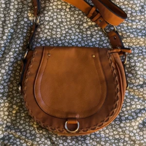 Snygg Saddle väska  - Super snygg crossbody väska i bra skick! 60-70 tal vajbs 😎( vet inte om den är så gammal dock! )  Köpt på myrorna för ett år sen, använd bara ett pa få gånger. Liten fläck på sidan av väskan. Skriv om det är nått ni undrar! (: