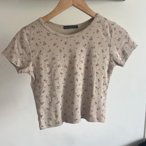 T-shirt - Säljer denna fina ljusrosa T-shirten med blommor på från brandy Melville i storlek S/M. Ganska bra skick, kan diskutera pris💕