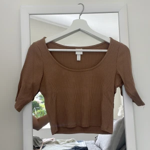 Brun ribbad top - En brun ribbad kort top till armbågarna. Bekväm och knappt använd. U-ringad.