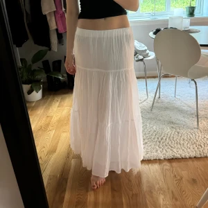 Vit maxikjol - Säljer en vit maxikjol från Ginatricot då den tyvärr inte kommer till användning. Helt ny, aldrig använd. Väldigt populär och trendig kjol. Vit volangkjol med dubbla tyg och resår i midjan💓 (ordinarie pris 400kr)