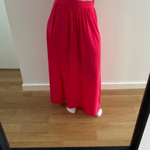 Rosa kjol - Superfin kjol i en korall-rosa/röd färg. Tunn och fladdrig! Fickor på sidorna. 
