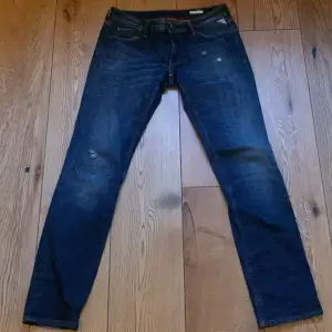 Mörkblå low waisted jeans med detaljer på bakfickan och röda detaljer vid midjan 