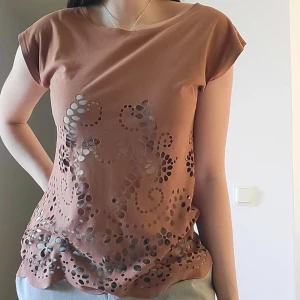 Y2K t-shirt med cutouts - Inköpt mellan år 2000-2010. T-shirt med cut-outs i ett häftigt mönster och med ett snyggt, lite figursytt fall. Mocka-aktigt tyg och väldigt mjuk. I superskick. Sista bilder återger färgen väldigt bra. Svarar på alla frågor.