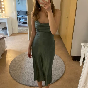 Grön klänning med snörning i ryggen - Klänning i superskönt material och fin snörning där bak som man kan justera själv och knyta. En perfekt finklänning som kan passa till bal mm. Aldrig använd endast testad. Säljer här då det var krångligt att skicka tillbaka. 