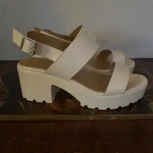 Vita sandaler med klack köpta från Scorett. Två små repor på vänster sko, se bild 2.