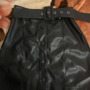 SKINNKJOL  - en jätte jätte fin skinnkjol med skärp, SOM GÅR ATT TA BORT. Den är använd Max 2 gånger därför jätte bra skick❤️ sitter otroligt fint på, har en dragkedja baktill och är i storlek 34/xs. 