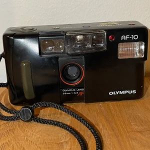 Kamera  - Olympus film kamera i fint men använt skick! Lite märken på blixten. Kameran är en analog film kamera (alltså inte en digital, utan men stoppar i film och lämnar in filmen och får den framkallad). Kameran är ej funktionstestad men har inte synliga skador 
