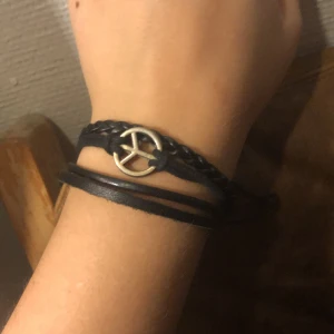 Läderarmband  - Ett läderarmband med justerbar storlek. Fredstecknet är i rostfritt stål och armbandet klarar sig bra i vatten
