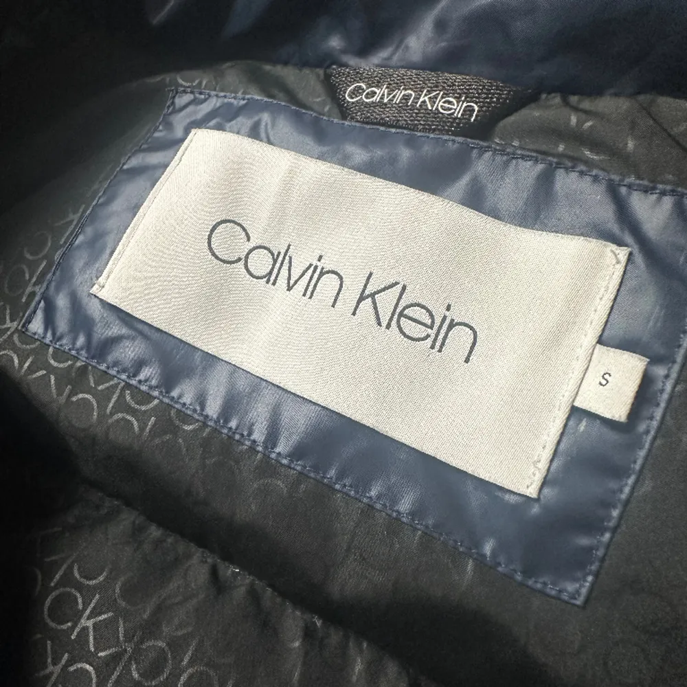 Säljer en dunjacka från Calvin Klein i en skimrande mörkblå färg. Den är extremt bra skick knappt använd!  Den är lite  figursydd, väldigt smickrande på☺️  Lite mindre i storleken lutar mer åt xs, päls ingår,   det är bara höra av sig vid frågor! . Jackor.