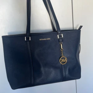Michael Kors - Superfin Michel Kors väska i bra skick och kvalitet. Rymlig men ändå classy, går att dra igen med dragkedja och massvis med förvaringsfack. En repa längre ned, se bild. Syns verkligen inte irl! Svart/jättemörk marinblå 