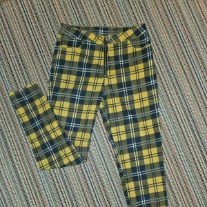 Rutiga byxor med dragkedja framtill - Byxorna är rutiga i svart och gul färg. De har inga användbara fickor framme men när back är fickorna användbara.