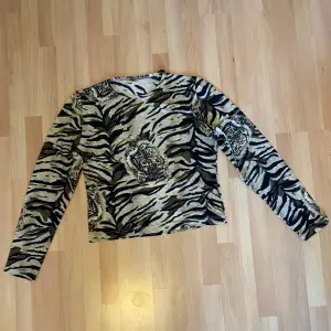 Långärmad croppad tröja med tiger motiv och lite glitter. Finns ingen lapp med storlek eller märke men köpt på humana och skulle säga att det är en storlek xs/s 