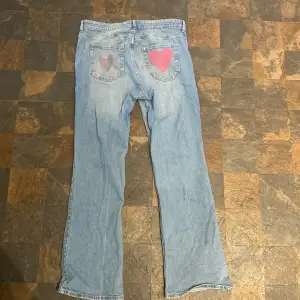 Ett par oanvända jeans som har två handmålade hjärtan på rumpan och som är lite utsvängda 