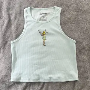 Supersöt ljusblå croptop med Tingeling broderat på framsidan. Användes en gång på en temafest för tidigt 2000-tal😂 gullig och väldigt skönt material! Står M som storlek men passar nog XS och S också