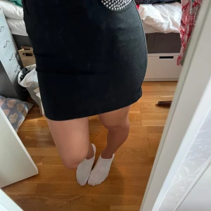 Kjol - Svart jeanskjol med nitar på ena fickan. Knappt använd. Stretchig. Stolek 40