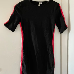 Kortärmad klänning med rödvita detaljer - Svart miniklänning med rödvita streck längs med sidorna. Aldrig använd! Från Nelly